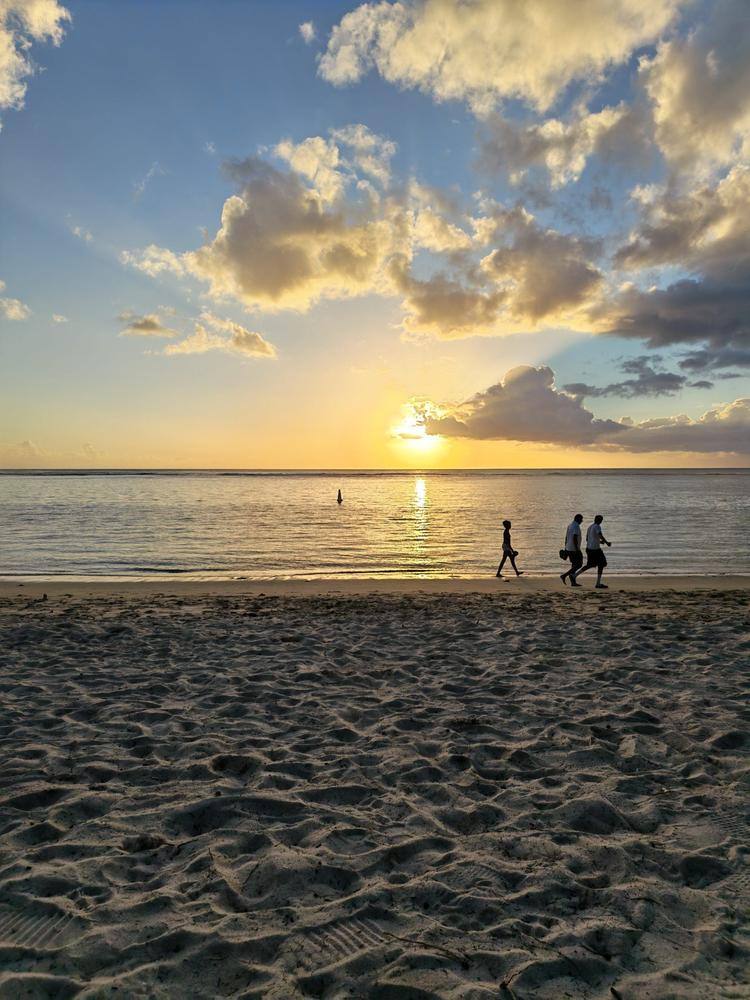 Coucher de soleil sur une plage mauricienne avec des promeneurs silhouettés