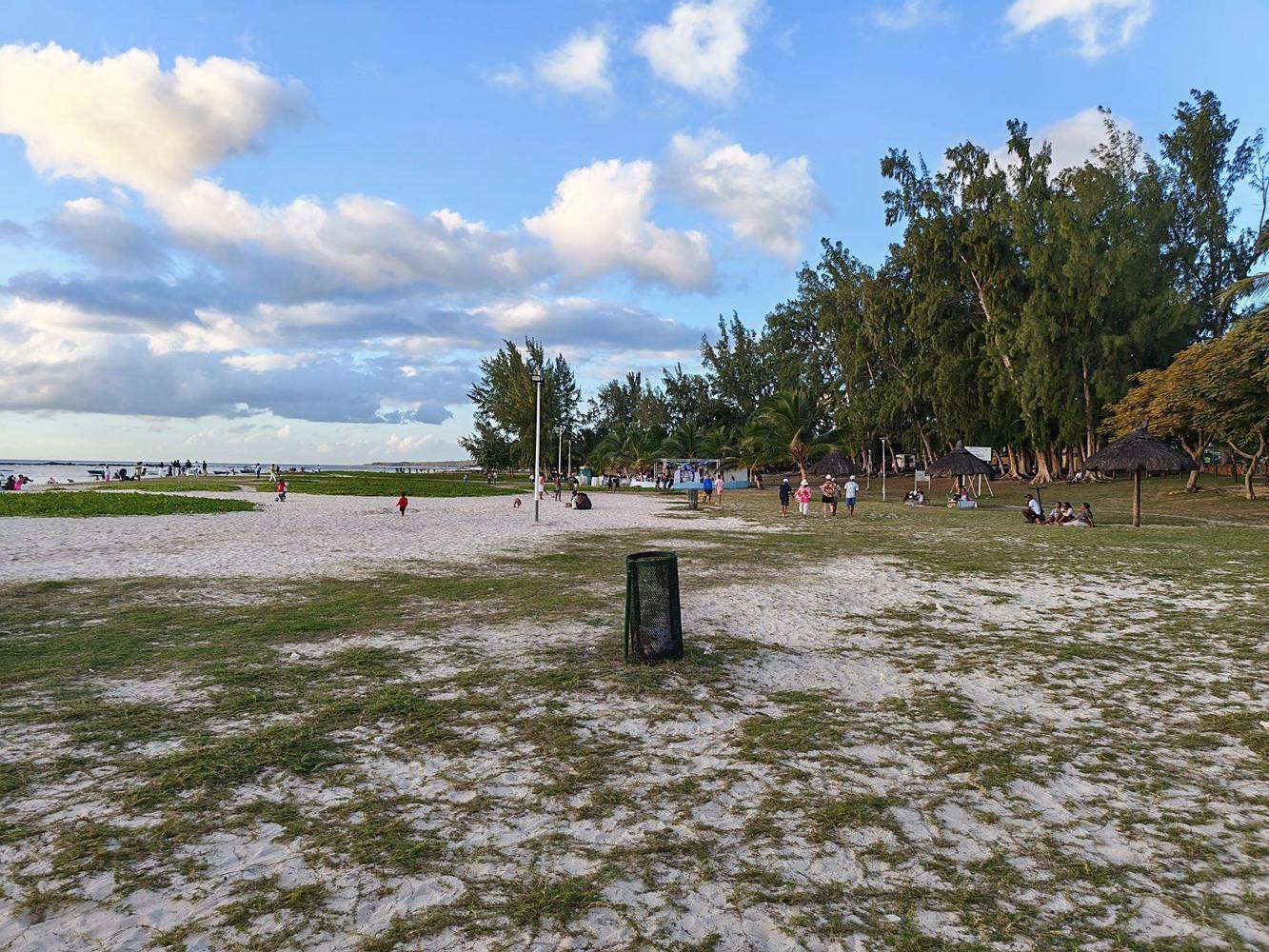 Plage publique aménagée à Maurice avec pelouse, filaos et cases de plage