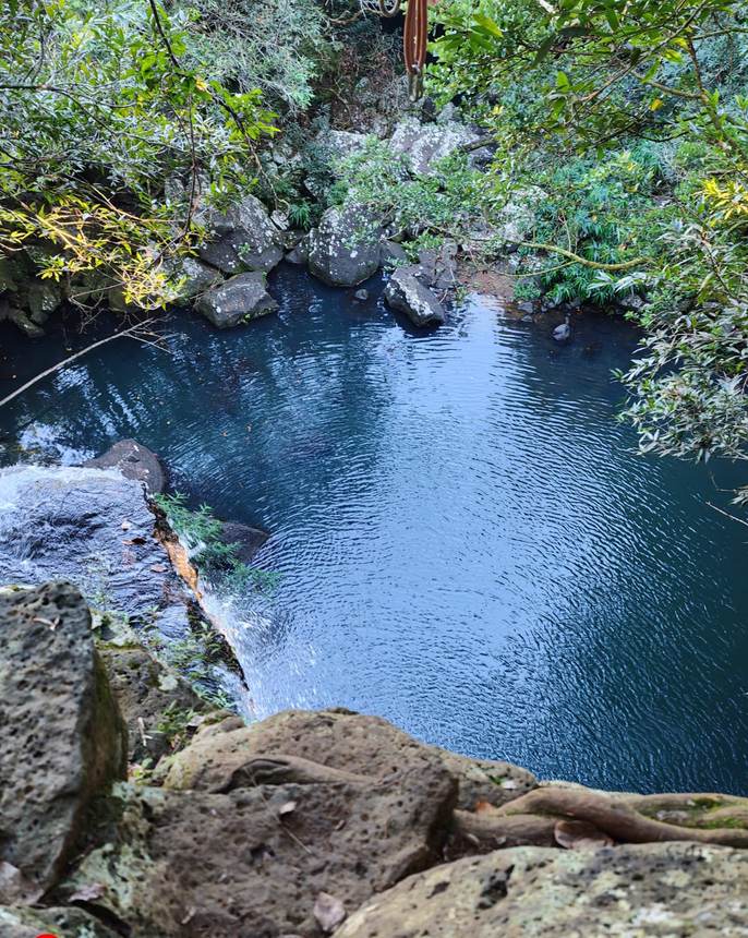 Un bassin d’eau sombre au pied d’une chute
