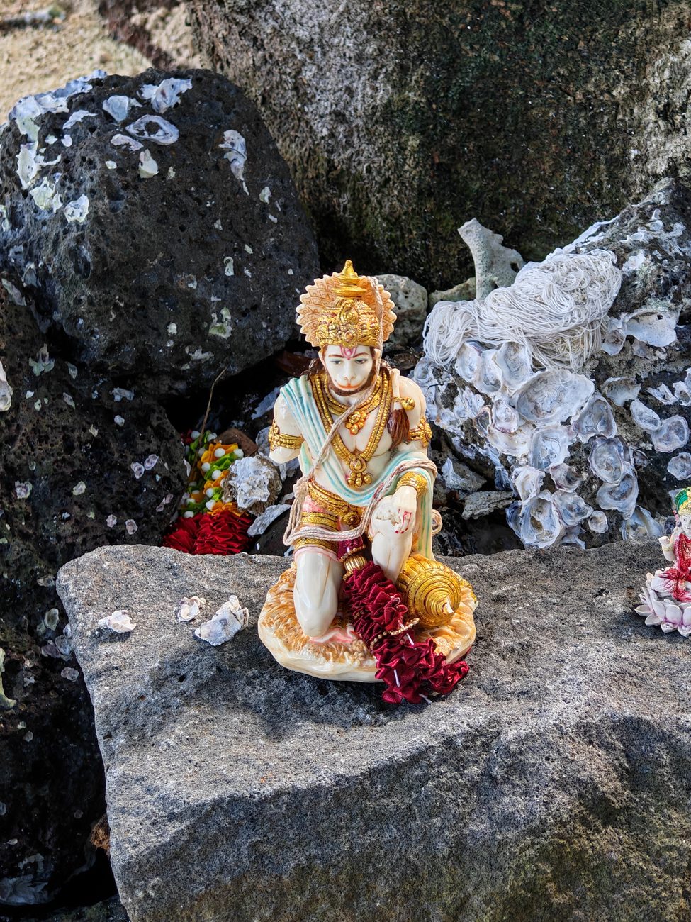 Une petite statue de Hanuman posée sur les rochers d'une plage